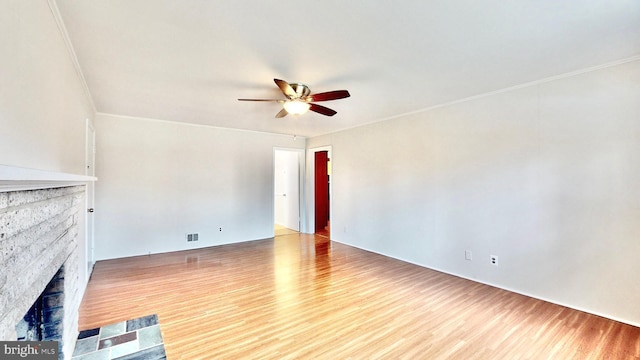 unfurnished living room with ornamental molding, a fireplace, a ceiling fan, and wood finished floors