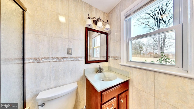 bathroom with toilet, tile walls, and vanity