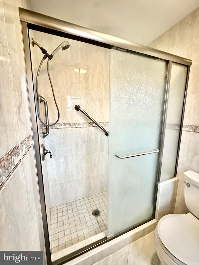 full bathroom with a shower stall, toilet, and tile walls