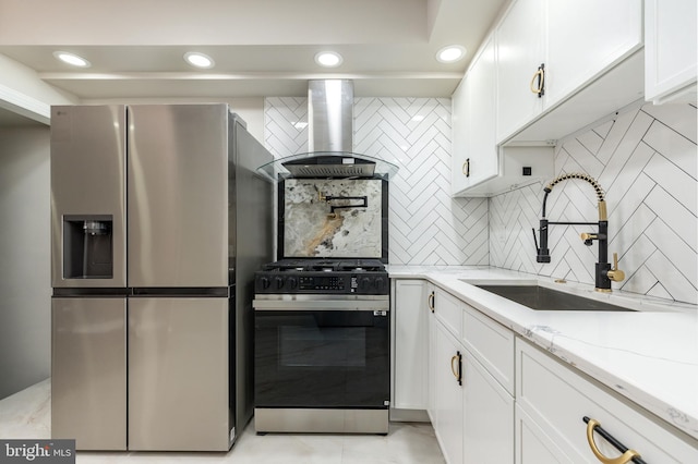 kitchen with a sink, gas range oven, white cabinetry, stainless steel fridge, and island range hood