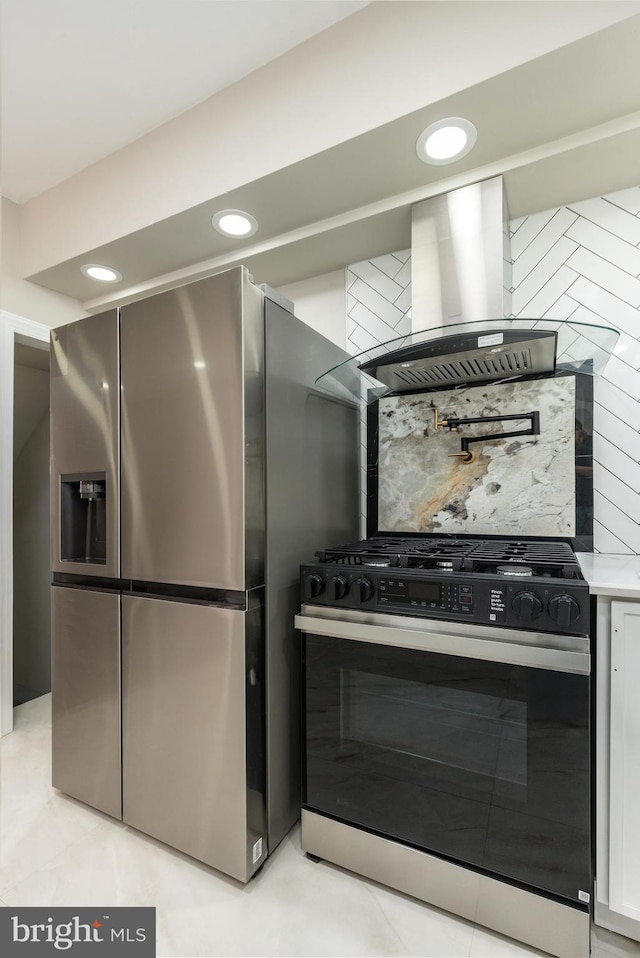 kitchen with backsplash, range with gas cooktop, wall chimney range hood, light countertops, and stainless steel refrigerator with ice dispenser