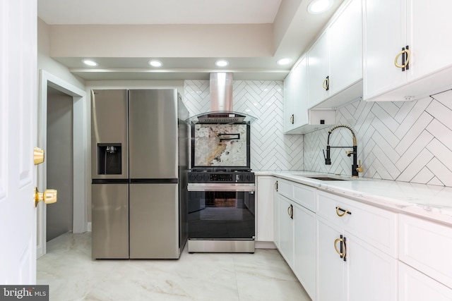 kitchen with light stone counters, a sink, gas stove, wall chimney exhaust hood, and stainless steel fridge with ice dispenser