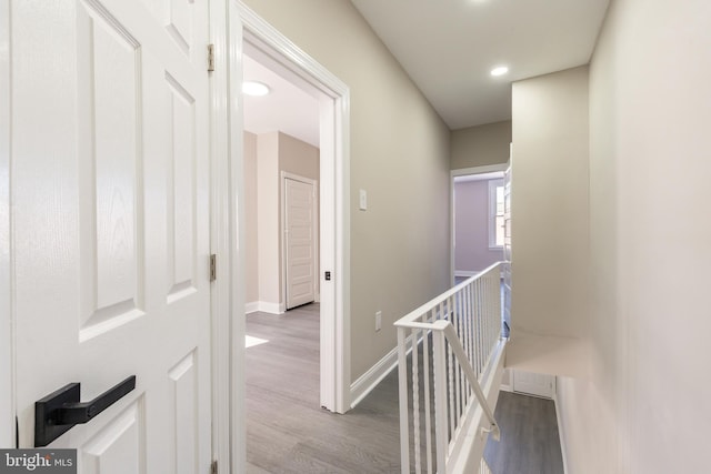 corridor featuring wood finished floors, recessed lighting, an upstairs landing, and baseboards