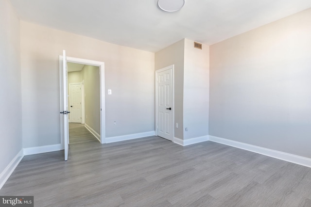 empty room with visible vents, baseboards, and wood finished floors