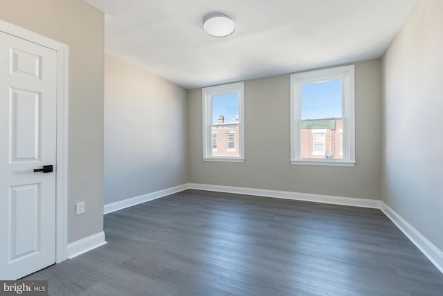 unfurnished room featuring baseboards and dark wood-style flooring