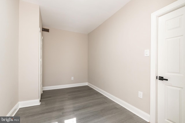 spare room featuring dark wood-style floors, visible vents, and baseboards