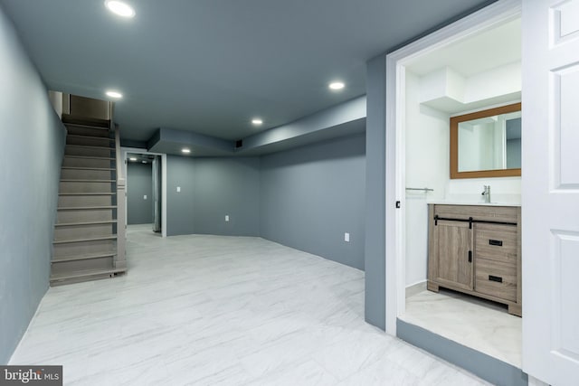 below grade area featuring stairway, recessed lighting, marble finish floor, and a sink