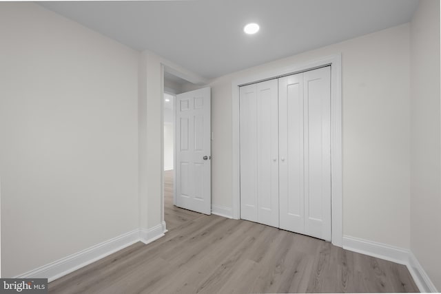 unfurnished bedroom with a closet, recessed lighting, baseboards, and light wood-style floors