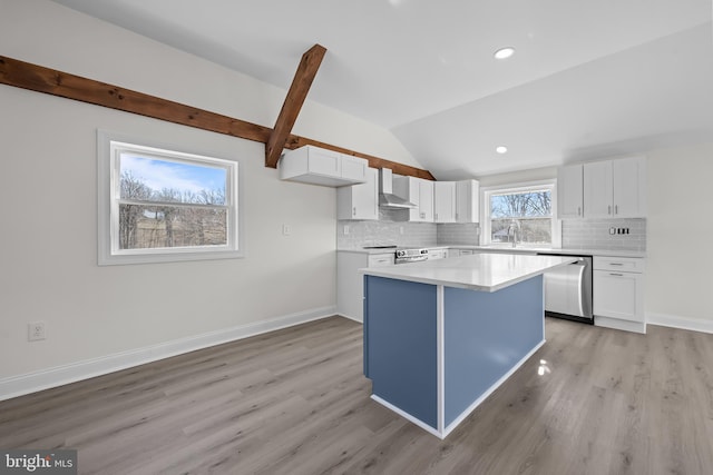 kitchen with lofted ceiling with beams, a kitchen island, stainless steel appliances, white cabinets, and wall chimney range hood