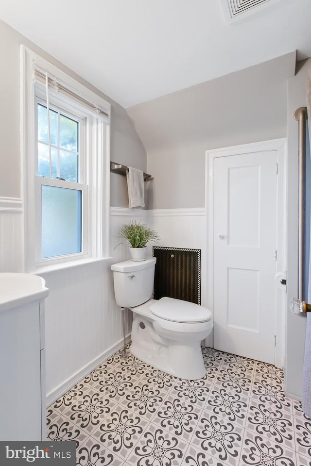 1175 Letort Rd, Conestoga, PA 17516 - bathroom with lofted ceiling, toilet, radiator heating unit, a wainscoted wall, and tile patterned flooring