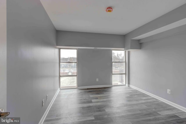 unfurnished room featuring plenty of natural light, wood finished floors, and baseboards