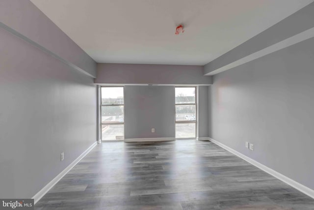 empty room with dark wood-style floors and baseboards