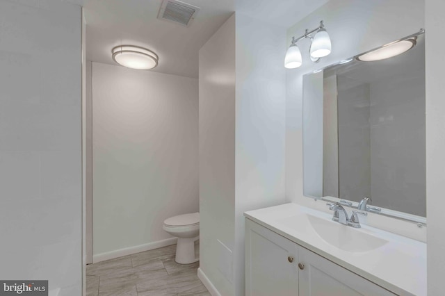 bathroom featuring vanity, toilet, baseboards, and visible vents