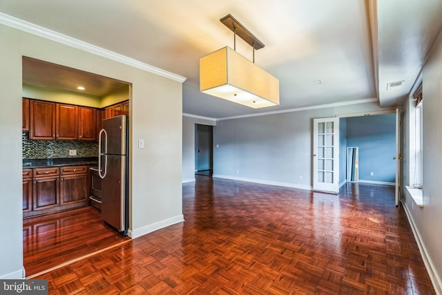 kitchen with dark countertops, backsplash, baseboards, and freestanding refrigerator