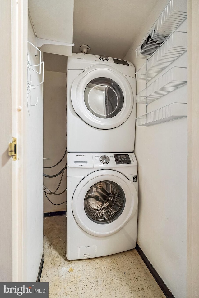 laundry area with stacked washer / drying machine, baseboards, and laundry area