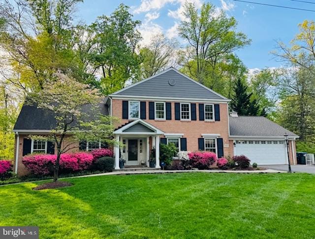 view of front of home with an attached garage, concrete driveway, and a front lawn