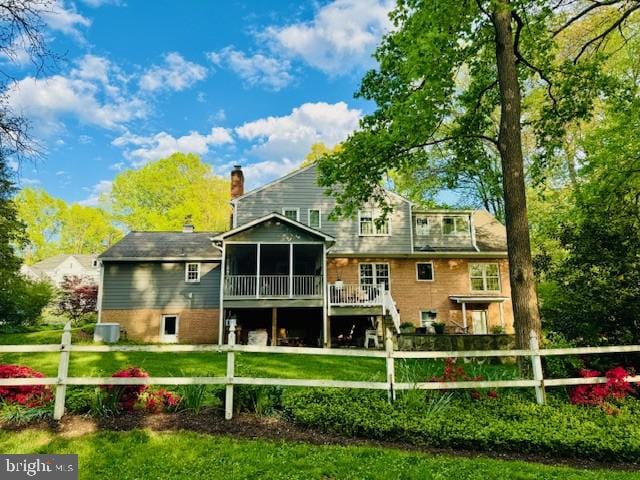 rear view of house featuring a sunroom, fence, a yard, and a chimney