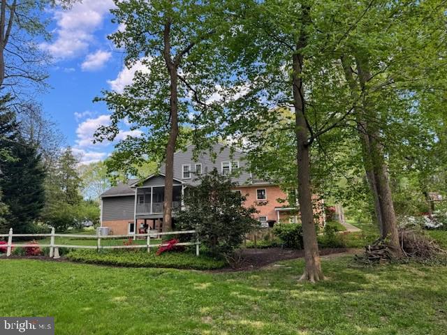 rear view of property with a lawn, fence, and a sunroom