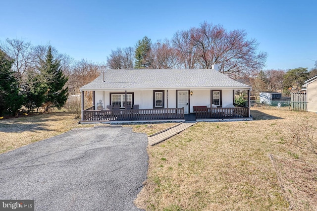 ranch-style house with a shingled roof, a porch, a front lawn, and stucco siding