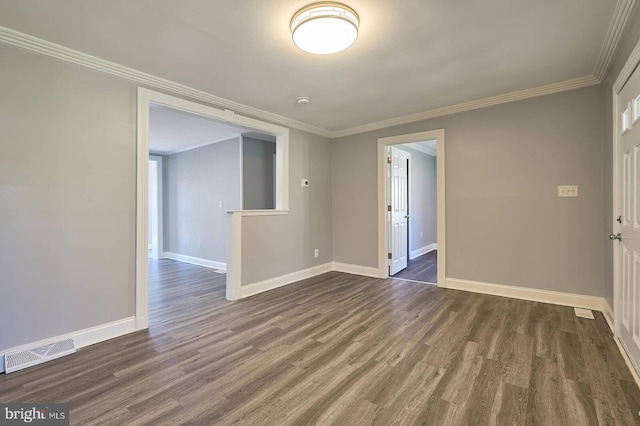 spare room with dark wood finished floors, visible vents, crown molding, and baseboards