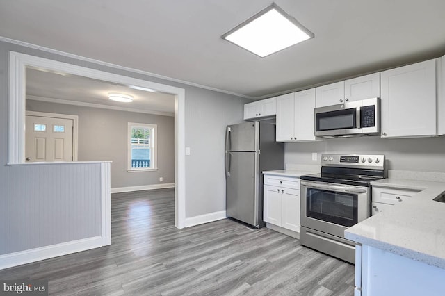 kitchen featuring light stone counters, white cabinetry, appliances with stainless steel finishes, crown molding, and light wood finished floors