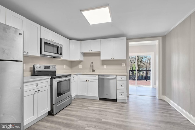 kitchen with a sink, stainless steel appliances, light wood finished floors, and light countertops