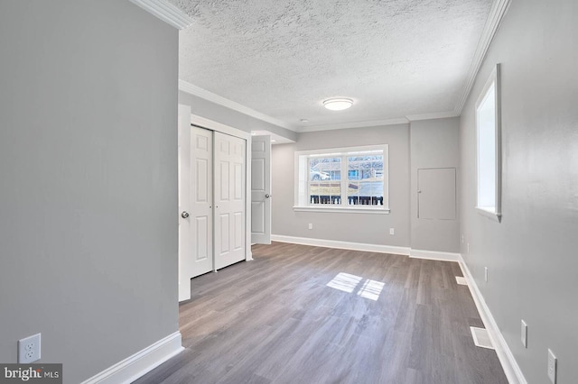 unfurnished bedroom featuring wood finished floors, baseboards, a closet, a textured ceiling, and crown molding