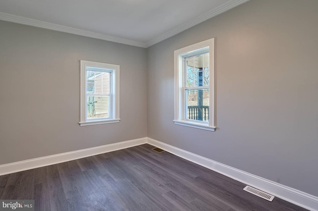 spare room featuring dark wood finished floors, visible vents, baseboards, and ornamental molding