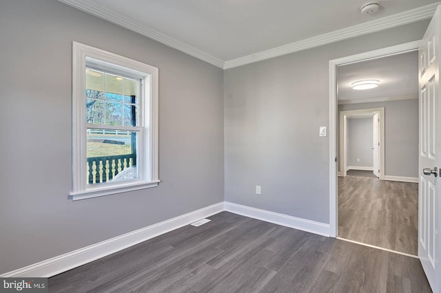 spare room featuring dark wood finished floors, crown molding, and baseboards