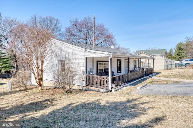 view of front facade featuring a front lawn, covered porch, and a chimney