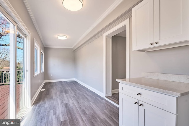 unfurnished dining area featuring baseboards, wood finished floors, and ornamental molding