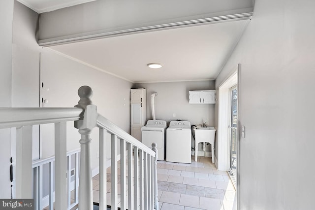 washroom featuring light tile patterned floors, cabinet space, a sink, crown molding, and washer and clothes dryer