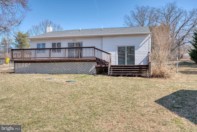 back of property with a deck, a chimney, and a yard