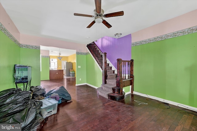 living area with stairway, a ceiling fan, baseboards, and wood-type flooring