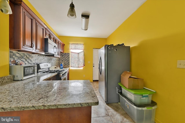 kitchen featuring light tile patterned floors, light stone counters, appliances with stainless steel finishes, decorative light fixtures, and backsplash