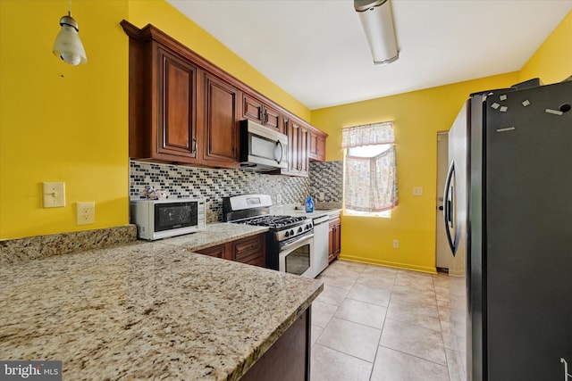 kitchen featuring tasteful backsplash, pendant lighting, light tile patterned floors, light stone counters, and stainless steel appliances