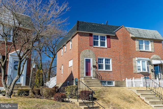 view of front of home featuring entry steps, fence, brick siding, and a shingled roof