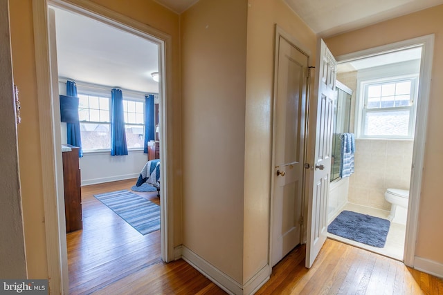 hallway with light wood-type flooring and baseboards