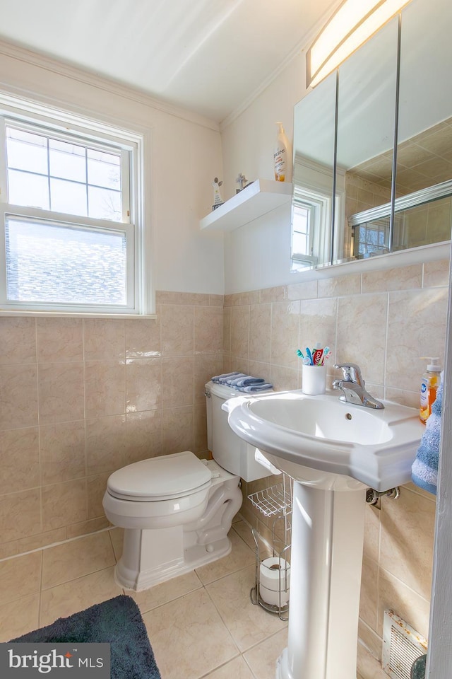 bathroom with tile patterned floors, toilet, tile walls, and crown molding