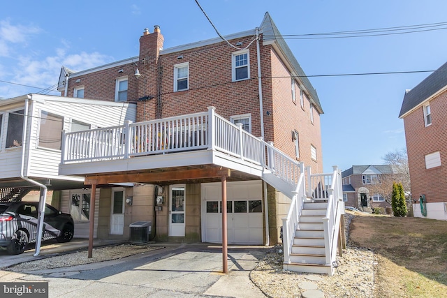 rear view of house with driveway, central AC, stairway, a garage, and brick siding