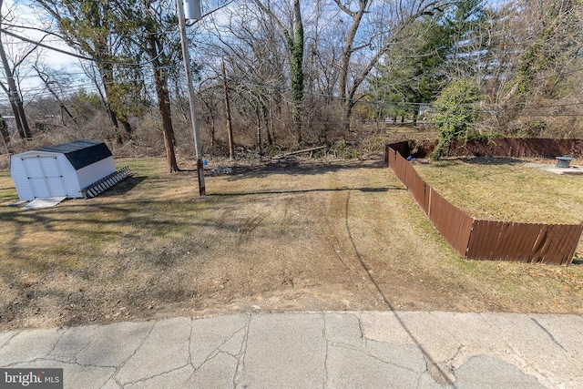 view of yard with an outdoor structure, fence, and a shed