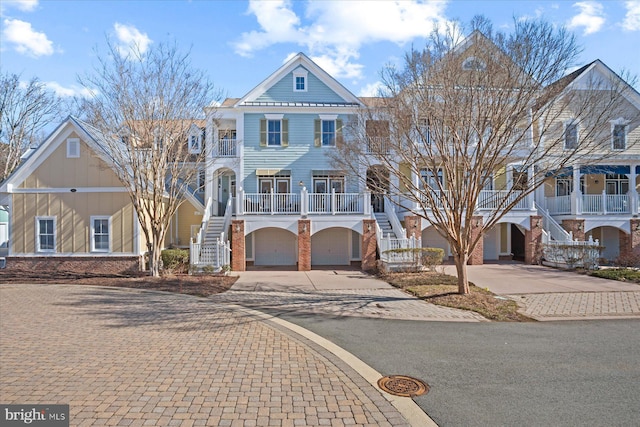 view of front of home featuring brick siding, stairs, covered porch, a garage, and driveway