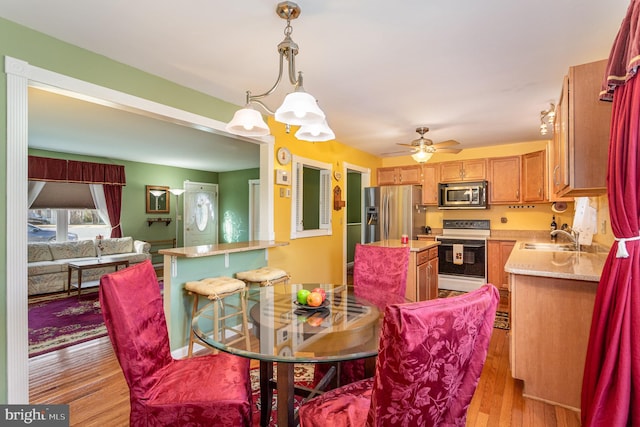 dining area with light wood-style flooring and a ceiling fan