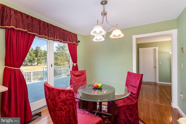 dining space with baseboards, an inviting chandelier, and wood finished floors