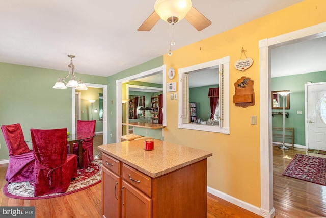 kitchen with a ceiling fan, decorative light fixtures, light wood-style floors, and baseboards