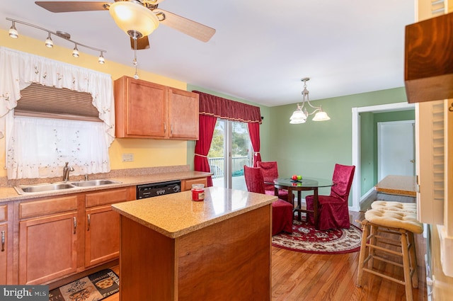 kitchen featuring ceiling fan, decorative light fixtures, dishwasher, wood finished floors, and a sink