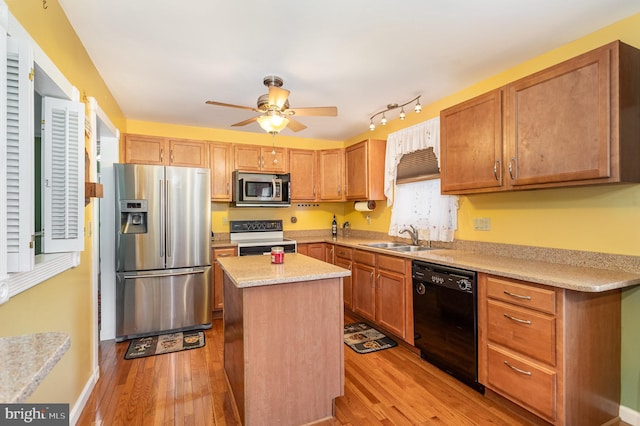 kitchen with light wood-style flooring, stainless steel appliances, ceiling fan, and a sink