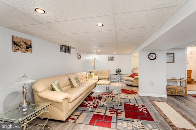 living area with a drop ceiling, baseboards, and wood finished floors