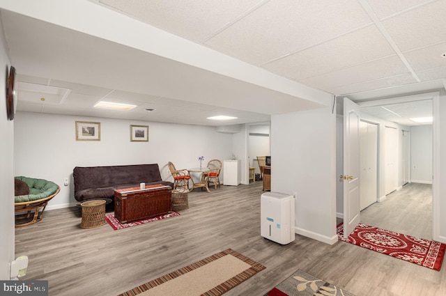 living room featuring wood finished floors, baseboards, and a drop ceiling