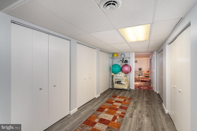 hallway featuring wood finished floors, visible vents, and a drop ceiling